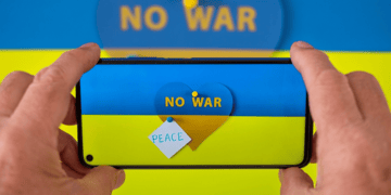 Mobile phone displaying Ukraine flag and antiwar message being held by male hands