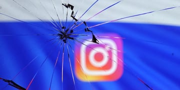 Russian flag and Instagram logo are seen through broken glas