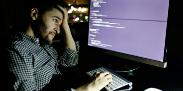 Tried worker in front of computer screen looking at data