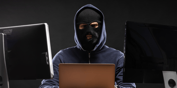 Man in balaclava with computer