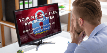 Businessman looking stressed as his computer files get encrypted