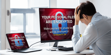 Office worker in despair in front of encrypted computer.