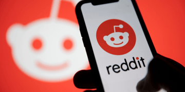 Hand holding mobile with Reddit logo