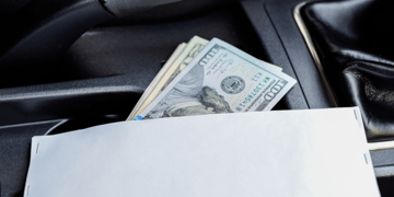 Gearstick inside car with envelope stuffed with cash