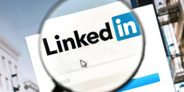 Magnifiying glass over LinkedIn logo on computer screen