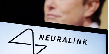 Neuralink logo seen, Elon Musk in the background