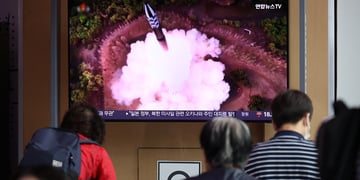 People watch a TV broadcasting a news report on North Korea firing a space satellite.