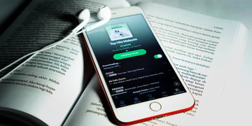 Spotify app seen on a smartphone that is on a book