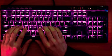 Hands of a glowing mechanical keyboard, typing