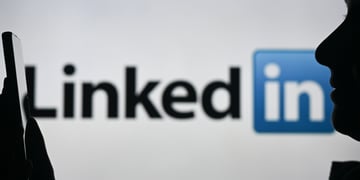 A person talking into their phone with the LinkedIn logo in the background.