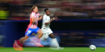 Two footballers chasing the ball in the Madrid derby.