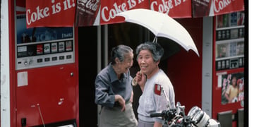 Two Japanese ladies in the 1980's, next to a vending machine.