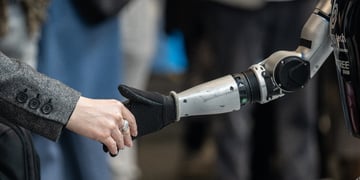 Human person shaking hands with Unitree humanoid robot