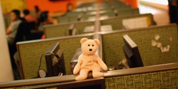 A teddy bear sitting on a top of a cubicle wall in a call center in the Philippines