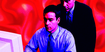 Manager watching over worker looking at screen