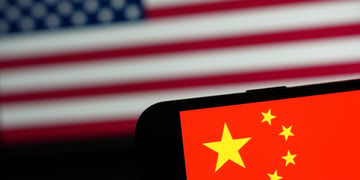 Chinese flag on phone in forefront, US flag in background