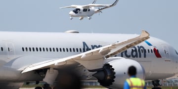 two white aircrafts with blurry staff in front, blue sky