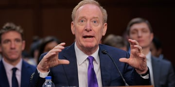 Microsoft Corporation President and Vice Chair Brad Smith with two men in the back