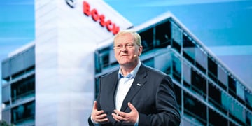Stefan Hartung in suit and blue shirt, glasses, glass building