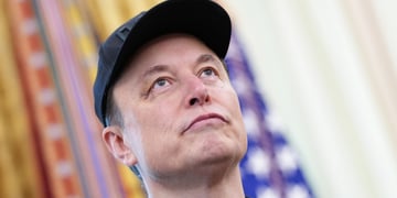 elon muskss face with black hat, looking up with blurry flads in the back