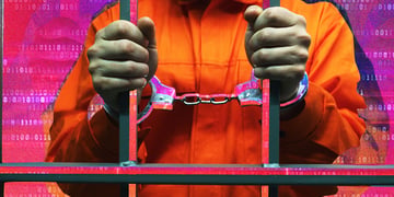 Handcuffed man behind the bars in jail; criminal; cybercriminal