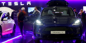 black tesla car on the right, open door on the left in a blue and purple lit room