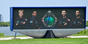 3 men and 1 blonde woman is space suits, poster, green grass