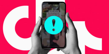 A pair of hands holding a cell phone with the TikTok logo and an exclamation mark.