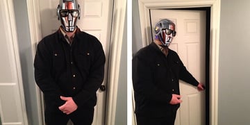 man in black jeans jacket, silver mask, opens white doors, blocks doors
