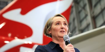 Qantas CEO Vanessa Hudson speaking to a microphone next to a plane