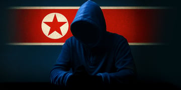 Hacker in hoodie sitting with North Korea flag in background