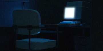 An empty chair in front of a desk with a laptop
