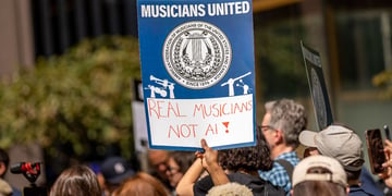 Protestors hold a poster saying "Real musicians not AI"