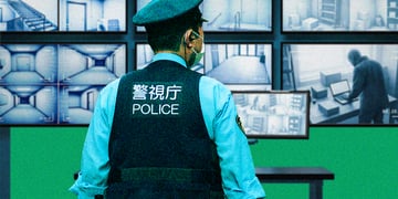 A Tokyo cop watching AI surveillance screens.
