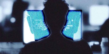 A silhouette of a human writing at a computer terminal.