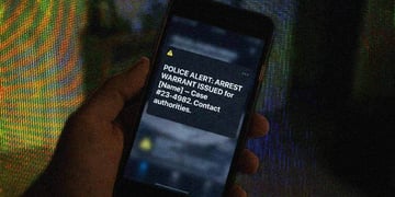 A phone on a blurred background, complete with digital arrest warrant.