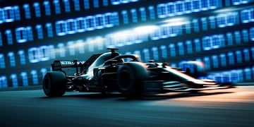 Black formula 1 car speed driving, baby blue blurry number wall behind it