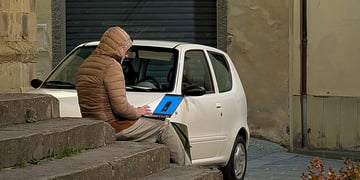 man working on laptop sitting outside on stairs