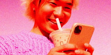 Alone young adult (Chinese) smiling at phone, milk tea nearby