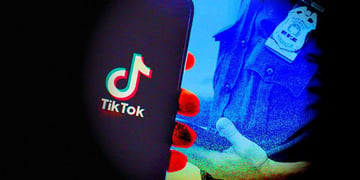 A smartphone with TikTok logo on the screen and a law enforcement officer