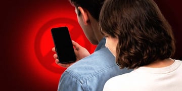 Person looking over shoulder at a smartphone with black screen
