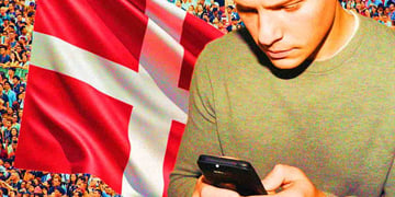 A person using a smartphone and Danish flag behind him