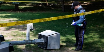 A broken camera with police standing over it.