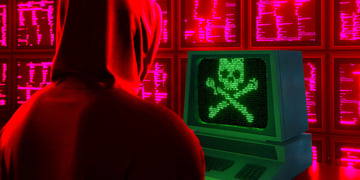 Hacker facing screen with scull; cyber threat