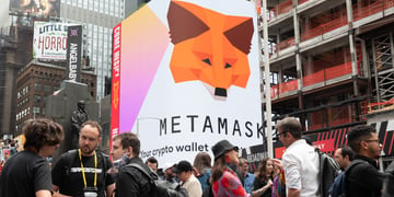 People stand by a MetaMask billboard in Times Square in New York City.