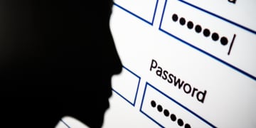 A silhouette of a person's face looking at a screen requiring a password