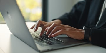 A close-up of hands type laptop keyboard