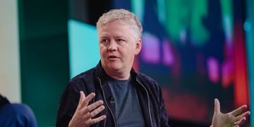 Cloudflare CEO Matthew Prince black suit, grey shirt, no collar, white hair, head turned left