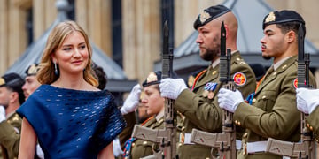 Princess Elisabeth of Belgium, blond hair, two army men in uniform, black guns, blue dress