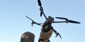 man in ukraine military uniform, facial mask, drone in hand, had in the blue sky, black